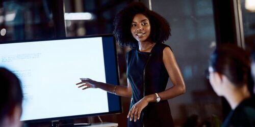 Woman stood next to screen doing a presentation. 