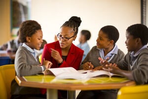 A teacher sitting with three children in a classroom