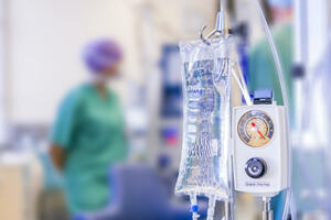 IV bag in the foreground with surgical theatre in the background