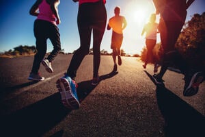 low angle back view of a group of friends jogging outdoors exercise together to promote brain health