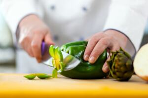 Chef with a chefs knife slicing a pepper
