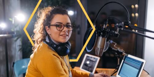 Woman on a laptop in front of a microphone. 