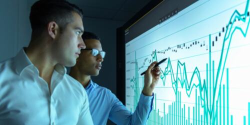 Two men looking at a whiteboard screen which displays a graph. 